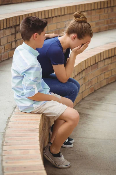 Haar triest vriend op stappen in campus troostende schooljongen — Stockfoto