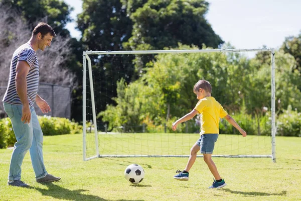 Far och son spelar fotboll i parken — Stockfoto