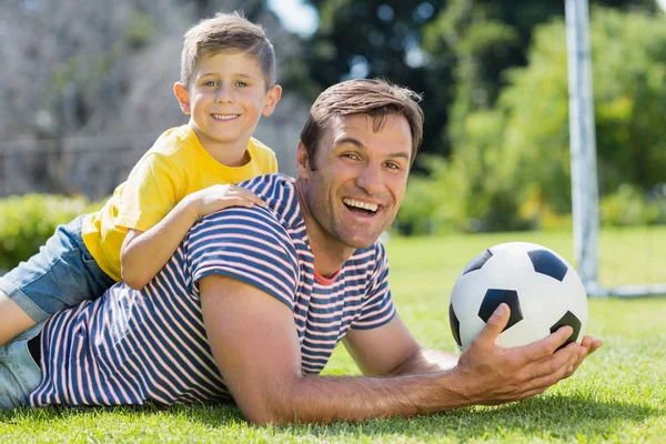 Far och son liggande på gräset i parken — Stockfoto