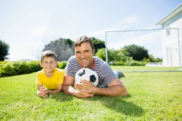 Vader en zoon liggen op gras in park — Stockfoto
