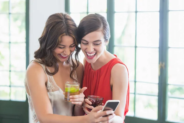 Vänner med cocktail glas medan du använder mobiltelefon — Stockfoto