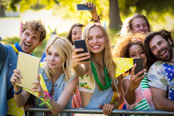 Amigos clicando fotos de seus telefones celulares e tablet digital — Fotografia de Stock