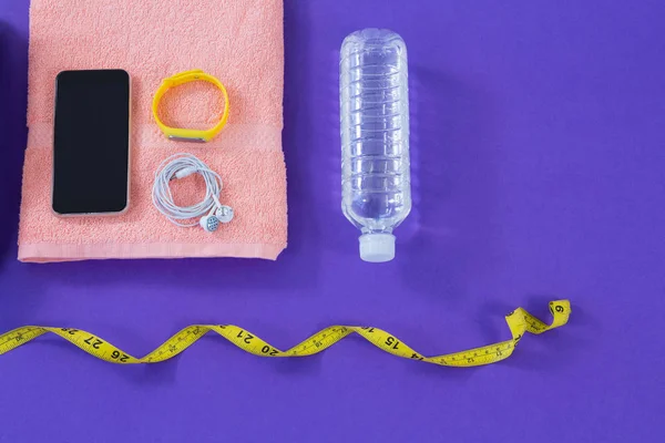 Garrafa de água, toalha, fita métrica, telefone celular com fones de ouvido e faixa de fitness — Fotografia de Stock