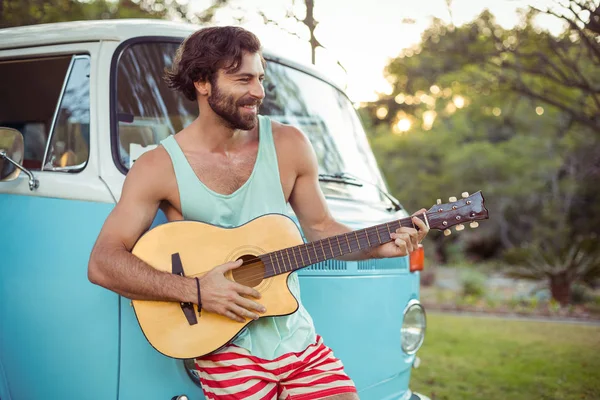 Člověk hrát na kytaru před campervan v kempu — Stock fotografie