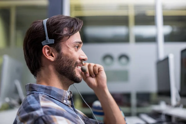 Smiling male customer service executive talking on headset at desk — Stock Photo, Image