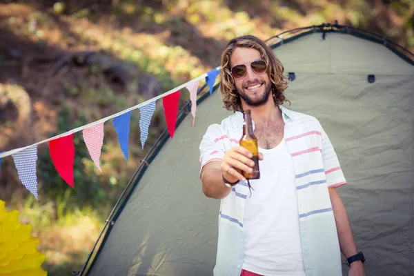 Mann zeigt Bierflasche auf Campingplatz — Stockfoto