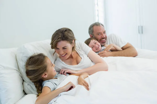 Family lying together on bed in bedroom — Stock Photo, Image