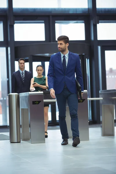 Businessman passing through turnstile gate — Stock Photo, Image