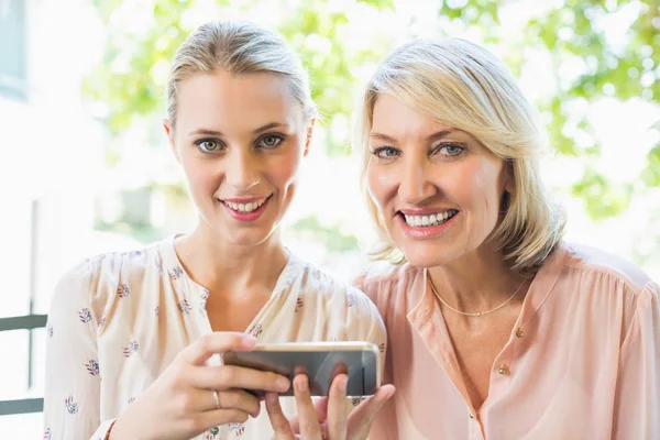 Amigos sosteniendo teléfono móvil en el restaurante — Foto de Stock