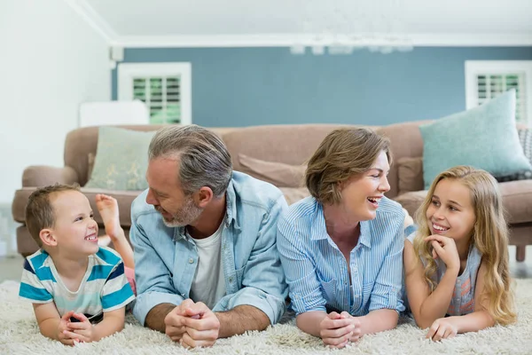 Famiglia sorridente sdraiata sul tappeto — Foto Stock