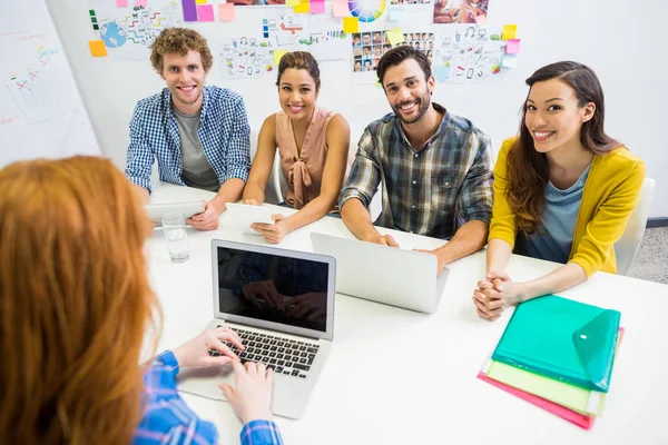 Verkställande diskuterar över laptop med hennes kolleger under möte — Stockfoto