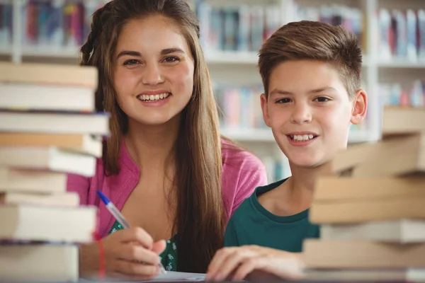 Χαμογελαστά τα παιδιά σχολείο κάνει την εργασία στη βιβλιοθήκη στο σχολείο — Φωτογραφία Αρχείου