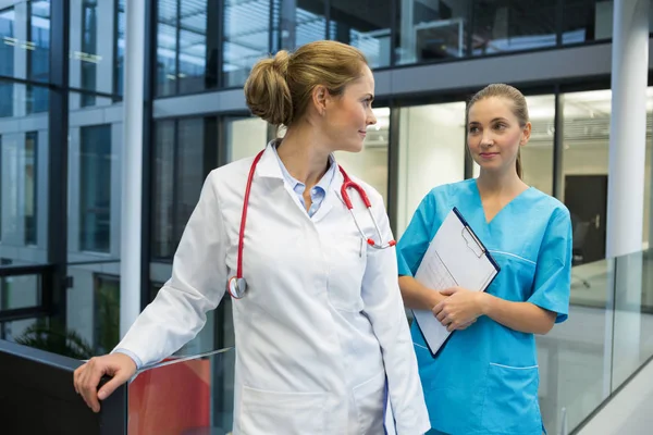 Female doctor and nurse standing in corridor — Stock Photo, Image