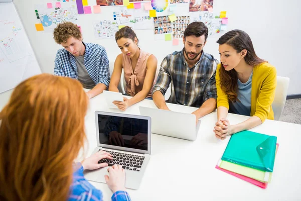 Executive dyskusji nad laptopa z kolegami podczas spotkania — Zdjęcie stockowe