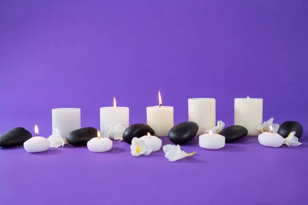 Velas, flores y piedras zen sobre fondo púrpura —  Fotos de Stock