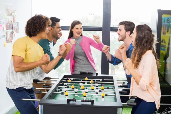 Executivos felizes torcendo enquanto jogam futebol de mesa — Fotografia de Stock