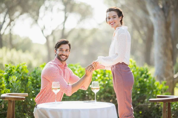 Man stelt een vrouw met een ring op zijn knie in het restaurant — Stockfoto