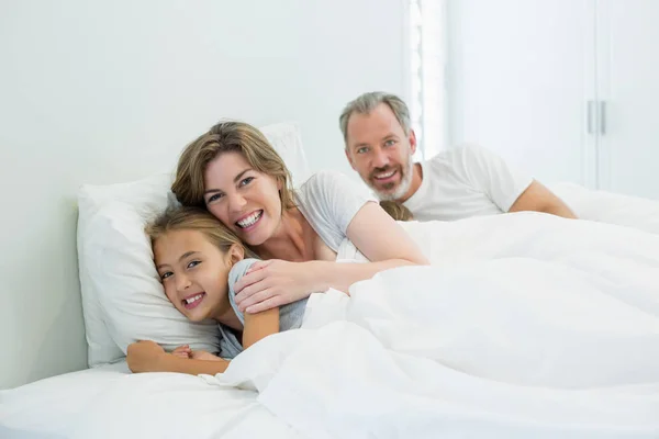 Семья лежит вместе на кровати в спальне — стоковое фото