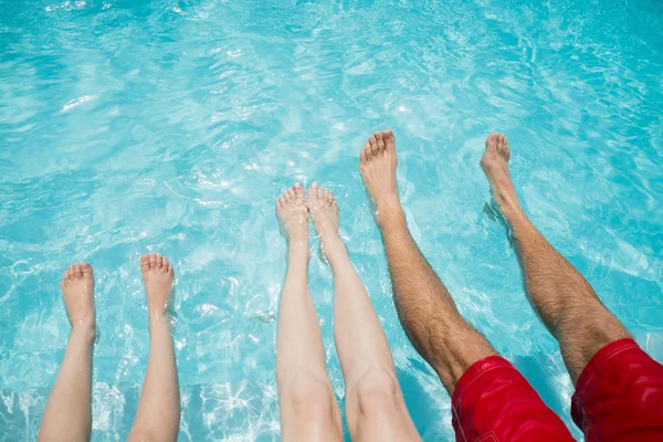 Familie zittend op zwembad en schudden hun benen — Stockfoto