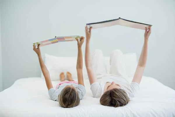 Mother and daughter on bed and reading book — Stock Photo, Image