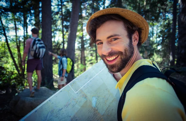 Gülümseyen adam ormanda harita tutarak — Stok fotoğraf