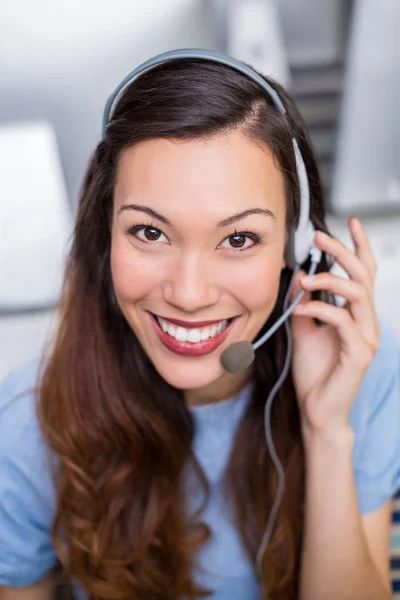 Portret van vrouwelijke klant dienst uitvoerend praten op headset aan balie — Stockfoto