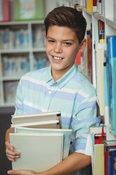 Portrait of schoolboy holding books in library — Stock Photo, Image
