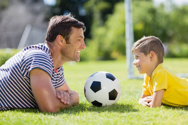 Father and son lying on grass in park — Stock Photo, Image