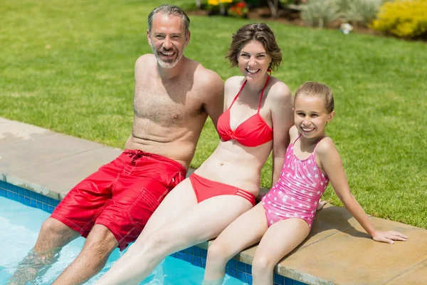 Родители и дочь сидят у бассейна — стоковое фото