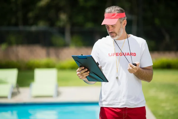 Nuoto allenatore guardando appunti vicino a bordo piscina — Foto Stock