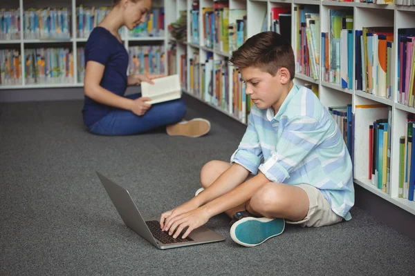 Colegial usando portátil en la biblioteca — Foto de Stock