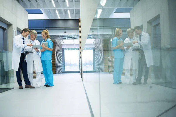 廊下でのタブレットの上を議論する医療チーム — ストック写真