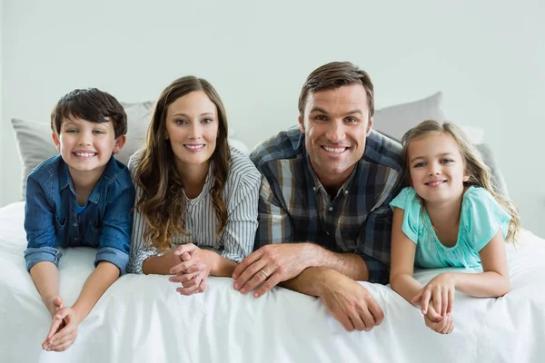 Familia sonriente acostada en la cama en el dormitorio — Foto de Stock