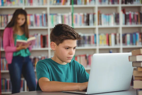 Iskolás használ laptop, iskolai könyvtár — Stock Fotó