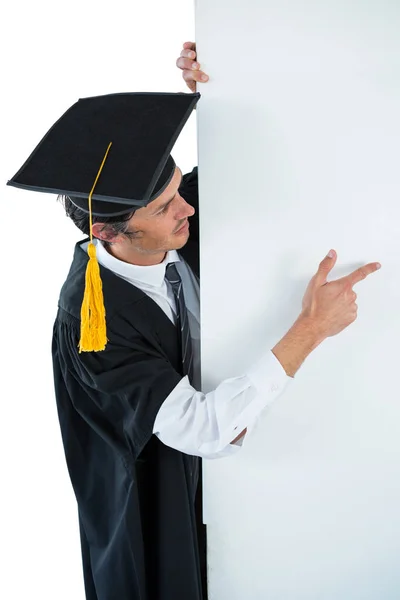 Hombre estudiante de posgrado detrás de un panel y señalando con el dedo — Foto de Stock