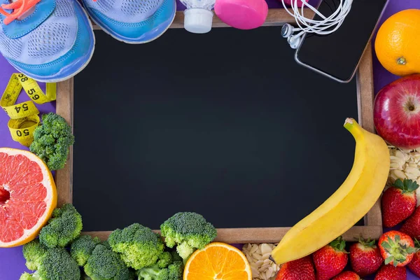 Leisteen omringd met fitness accessoires en diverse groenten en fruit — Stockfoto