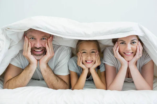 Familia acostada debajo de la manta en la cama en casa —  Fotos de Stock