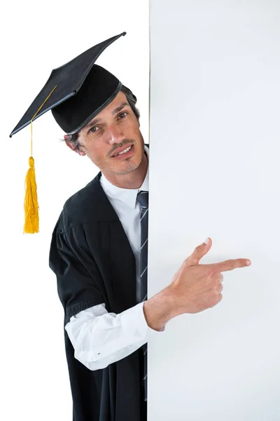 Male graduate student behind a panel and pointing with finger — Stock Photo, Image