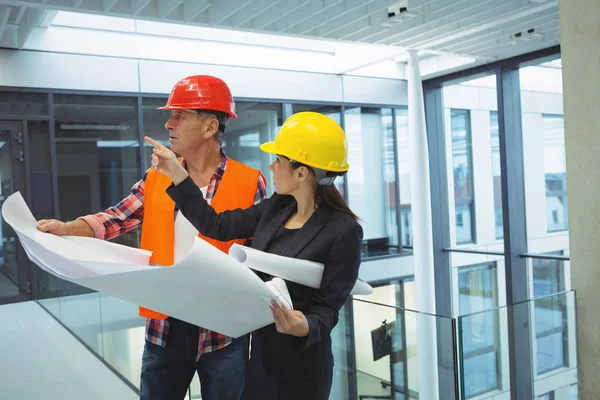 Businesswoman discussing over blueprint with an architect — Stock Photo, Image