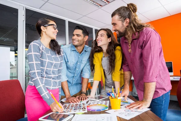 Diseñadores gráficos sonrientes trabajando sobre fotos en el escritorio —  Fotos de Stock