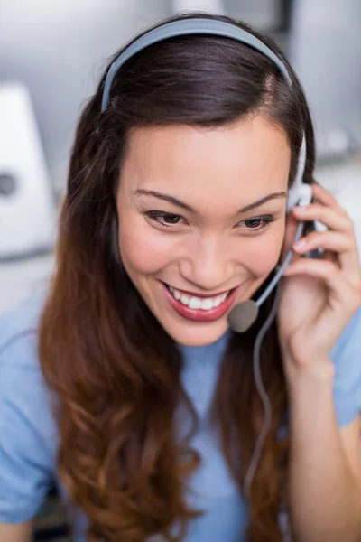 Lächelnde Kundendienstmitarbeiterin im Gespräch auf dem Headset am Schreibtisch — Stockfoto