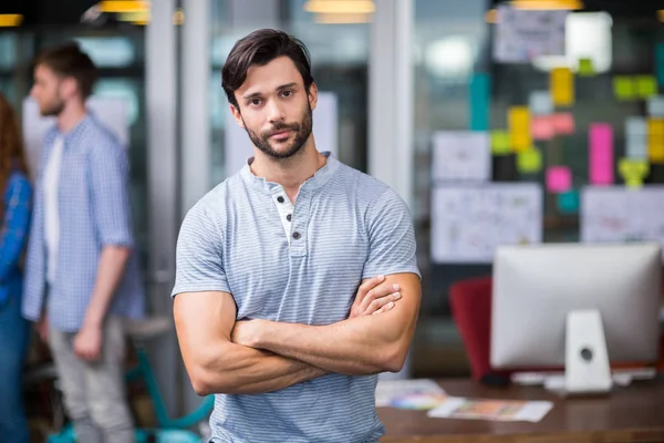 Male executive standing with arms crossed in office — Stock Photo, Image