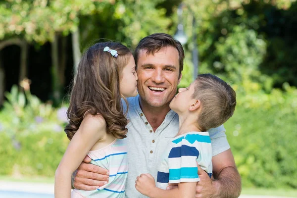 Portrait of father receiving kisses from son and daughter — Stock Photo, Image