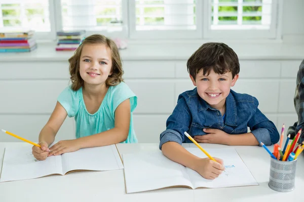 Siblings studying together in living room — Stock Photo, Image