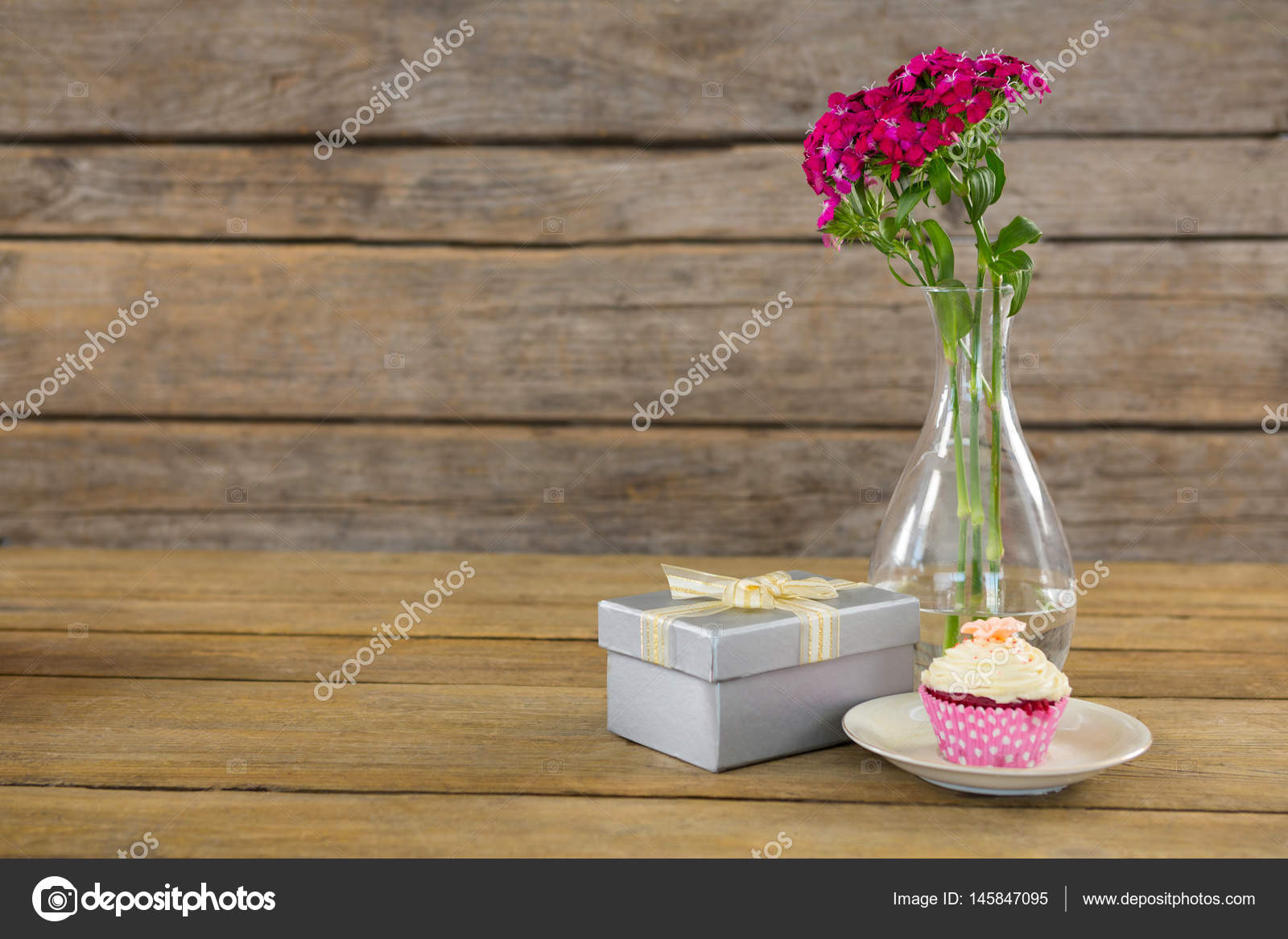 Gift Box And Flower Vase With Cupcake In Plate On Wooden Plank