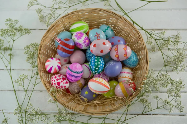 Basket with painted Easter eggs on wooden background — Stock Photo, Image