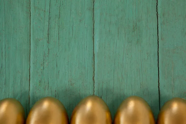 Golden Easter eggs arranged on wooden surface — Stock Photo, Image