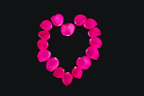 Szív alakú, fekete háttér ellenében alkotó rózsaszirom — Stock Fotó