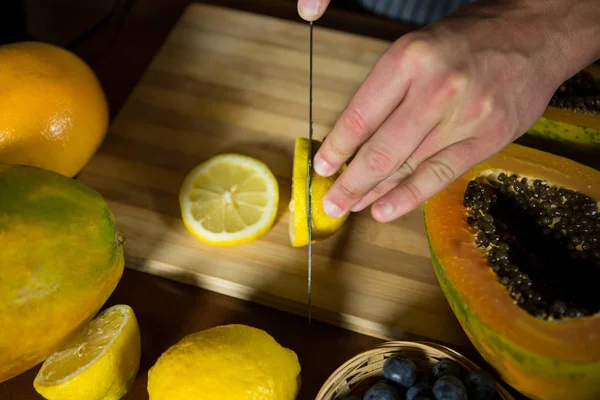 Staff slicing lemon on chopping board — Stock Photo, Image