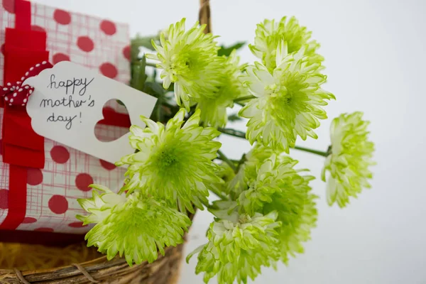 Caixa de presente e um monte de flores amarelas em cesta de vime com feliz mãe dia tag — Fotografia de Stock